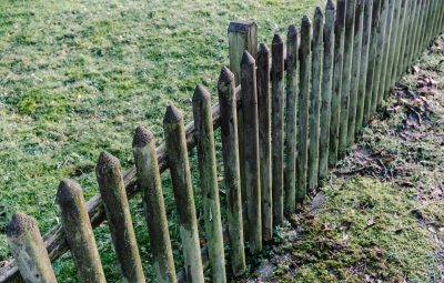 A rustic, weathered wooden fence in a grassy, outdoor garden setting. Perfect for nature photography.